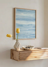 Gerahmtes Wandbild mit unregelmäßigen horizontalen Linien in Hellblau, Mittelblau und Weiß, ruhiger abstrakter Komposition, von Wasser inspiriert und mit küstennaher Anmutung. Erhältlich auf kudeko.com