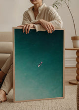 Wandbild mit einsamem Surfer auf weißem Surfbrett in türkisfarbenem und blaugrünem Meer, mit Luftperspektive und klarer Bildsprache im fotografischen Stil. Erhältlich auf kudeko.com