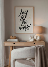 Wandbild mit dem Schriftzug Joy to the World in schwarzer Kalligrafie auf hellbeigem Hintergrund, goldenen Sternen und minimalistischem Typografie Stil. Erhältlich auf kudeko.com
