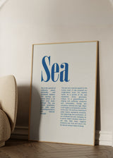 Gerahmtes Wandbild mit blauer Typografie, hervorgehobenem Wort Sea, beigem Hintergrund und minimalistischem editorialem Stil für moderne Wandgestaltung. Erhältlich auf kudeko.com