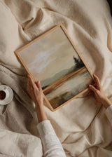 Tableau de paysage avec lac paisible au premier plan, montagnes estompées, ciel beige lumineux, arbres sombres, palette crème sable brun et gris vert, style nature contemporain. Disponible sur kudeko.com