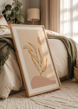 Gerahmtes Wandbild mit stilisiertem Blattzweig in ockerfarbener Linie, beigem Hintergrund, organischen Formen in Sand und Altrosa, im minimalistischen natürlichen Stil. Erhältlich auf kudeko.com