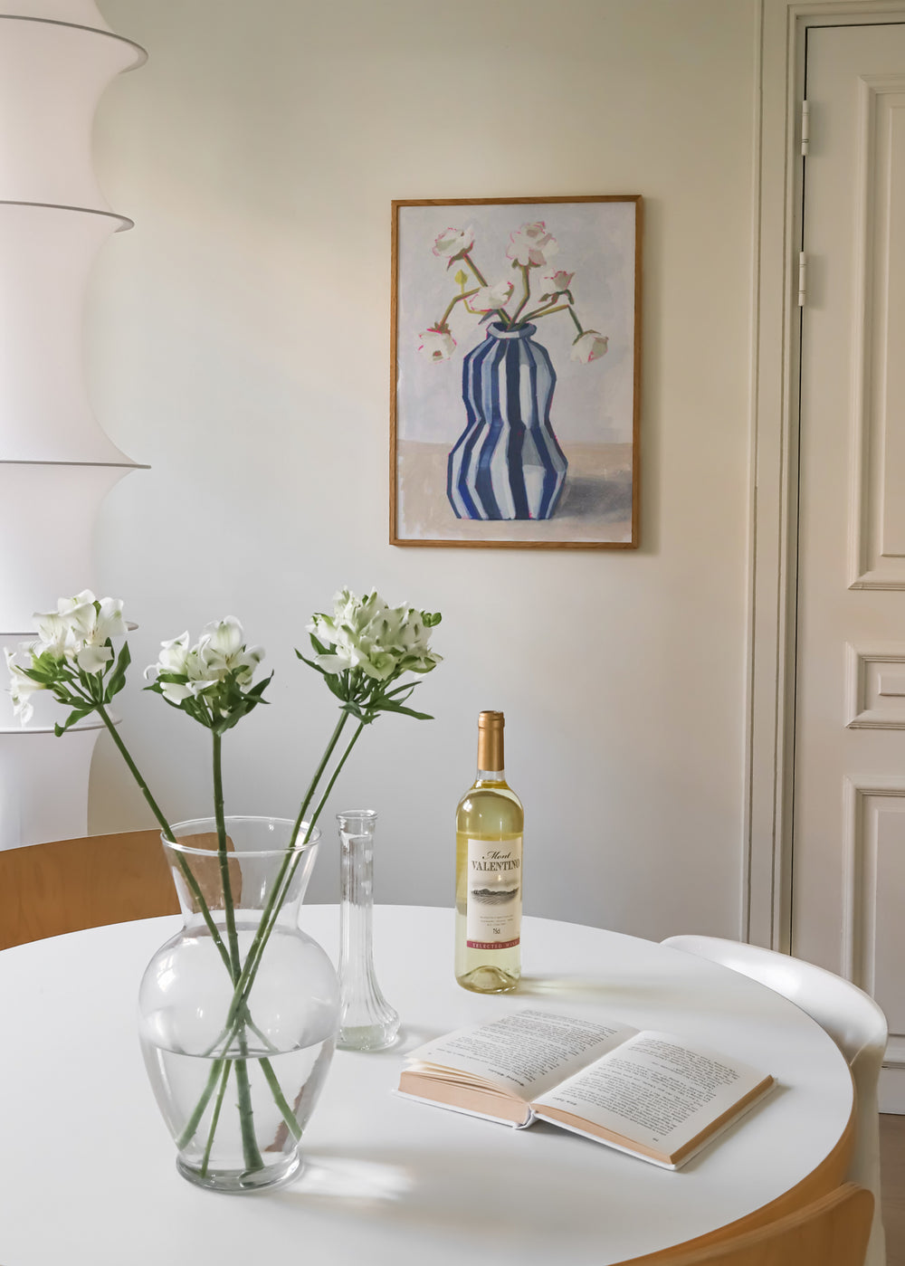 Gerahmtes Wandbild mit weißen Blumen, grünen Stielen, blau weiß gestreifter Vase, hellem Hintergrund und elegantem floralem Stil im nordischen Look. Erhältlich auf kudeko.com