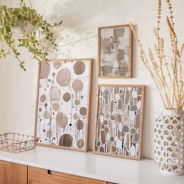 Conjunto de tres cuadros con formas abstractas de círculos, líneas y figuras orgánicas en beige, taupe, gris y blanco, de estilo abstracto. Disponible en kudeko.com