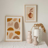 Tableau encadré avec composition de vases et poteries aux formes organiques, en terracotta, beige, sable et brun doux sur fond crème, dans un style minimaliste. Disponible sur kudeko.com