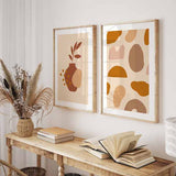Tableau encadré avec formes organiques abstraites en beige, terracotta, brun et crème, composition équilibrée au style abstrait pour décoration murale contemporaine. Disponible sur kudeko.com