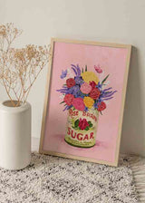 Cuadro de ramo de flores rosas, violetas y amarillas en lata vintage sobre fondo rosa, con mariposas y estilo floral delicado. Disponible en kudeko.com