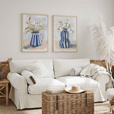Cuadro con ramo de flores blancas y rosas en jarra de rayas azules, fondo claro y composición de estilo floral. Disponible en kudeko.com