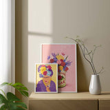 Cuadro con retrato femenino inspirado en Frida Kahlo, con flores grandes en amarillo, fucsia, azul y violeta, fondo crema y estilo ilustración. Disponible en kudeko.com
