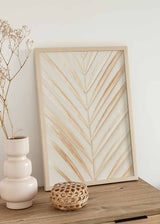 Cuadro de hoja de palma simétrica en tonos beige, arena y dorado suave sobre fondo blanco, de estilo minimalista. Disponible en kudeko.com