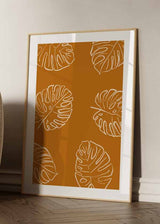Cuadro con hojas tropicales monstera en contornos blancos sobre fondo terracota cálido, composición botánica limpia de estilo minimalista. Disponible en kudeko.com