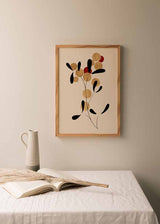 Cuadro con composición botánica abstracta de círculos dorado arena, formas negras orgánicas, detalles rojos y fondo beige claro de estilo abstracto. Disponible en kudeko.com