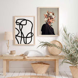 Wandbild mit surrealistischem Frauenporträt aus weißen Magnolien, rosa Blüten, braunen Blättern und feinen Zweigen auf beigem Hintergrund, im ruhigen Illustrationsstil. Erhältlich auf kudeko.com