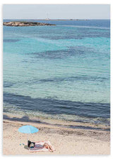 Quadro de praia mediterrânica com mar turquesa, areia clara, guarda-sol azul, duas pessoas a descansar e estilo fotográfico em tons de azul, bege e branco. Disponível em kudeko.com