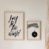 Wandbild mit dem Schriftzug Joy to the World in schwarzer Kalligrafie auf hellbeigem Hintergrund, goldenen Sternen und minimalistischem Typografie Stil. Erhältlich auf kudeko.com