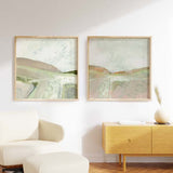 Tableau carré avec paysage abstrait de collines douces, bande lumineuse centrale, ciel clair, beige, rose poudré, crème et vert sauge, style nature et paysage épuré. Disponible sur kudeko.com