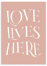 Cuadro con frase LOVE LIVES HERE en letras blancas grandes sobre fondo rosa empolvado, composición tipográfica elegante de estilo con frases. Disponible en kudeko.com