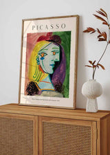 Quadro com retrato feminino cubista, boina vermelha, cabelo amarelo, rosto em tons azulados, fundo verde e rosa, estilo de ilustração com linhas marcadas e composição artística. Disponível em kudeko.com
