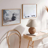Horizontales Wandbild mit schwarzer Dampflok auf verschneiten Gleisen, dichtem weißem Rauch, winterlicher Landschaft in Grau, Weiß und Schwarz, im fotografischen Retro Stil. Erhältlich auf kudeko.com