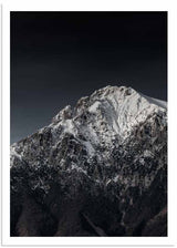 Fotografisches Wandbild eines schneebedeckten Berges mit felsigem Gipfel, dunklem Himmel sowie weißen, grauen und schwarzen Tönen in elegantem Stil. Erhältlich auf kudeko.com