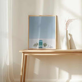 Cuadro de puerta azul turquesa en fachada blanca con macetas simétricas, bicicleta ligera, cielo azul claro y estilo fotográfico mediterráneo. Disponible en kudeko.com