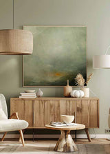 Cuadro cuadrado de paisaje brumoso con colinas oscuras, cielo amplio verde grisáceo, beige suave y luz anaranjada tenue, de estilo naturaleza y paisajes. Disponible en kudeko.com
