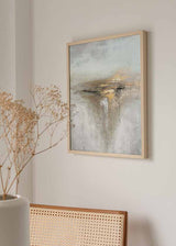 Quadro abstrato emoldurado com composição em branco quebrado, bege, cinzento pérola e detalhes dourados, textura difusa e faixa central escura, num estilo contemporâneo sóbrio. Disponível em kudeko.com