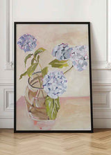 Cuadro de hortensias azul lavanda y blancas en jarrón de cristal, con hojas verdes, fondo beige rosado y estilo floral. Disponible en kudeko.com