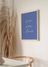 Cuadro con frases Sun Sea Love en tipografía manuscrita blanca sobre fondo azul lavanda liso, de estilo con frases. Disponible en kudeko.com
