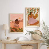 Wandbild mit sitzender Frau im Wasser, grafischer Sonne, Palmen, tropischen Pflanzen sowie Altrosa, Terrakotta, Lila und Grün im gerahmten Illustrationsstil. Erhältlich auf kudeko.com
