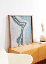 Tableau carré avec formes abstraites ondulées en bleu turquoise, gris, blanc et noir, fins détails dorés, fond texturé et style contemporain. Disponible sur kudeko.com