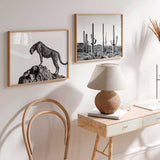 Horizontales Wandbild mit Gepard in Schwarz-Weiß auf einem Felsen, geflecktes Fell, heller Hintergrund, sachlicher fotografischer Tierstil mit klarer Komposition. Erhältlich auf kudeko.com