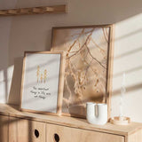 Quadro emoldurado com frase inspiradora em inglês, três árvores douradas sobre fundo branco, tipografia manuscrita preta e estilo decorativo com mensagem simples. Disponível em kudeko.com