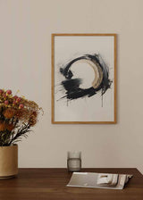 Quadro com grande forma circular em preto e bege, fundo branco pérola, composição abstrata com salpicos, traços largos e estilo contemporâneo minimalista. Disponível em kudeko.com