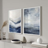 Conjunto de dois quadros com formas abstratas inspiradas na água e no horizonte, em azul-marinho, cinzento fumado, branco e estilo abstrato contemporâneo. Disponível em kudeko.com