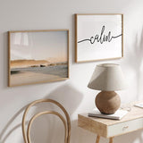 Cuadro horizontal de playa en Costa Rica con olas suaves, arena clara, bruma dorada, montañas al fondo y estilo fotográfico en tonos beige y azul grisáceo. Disponible en kudeko.com