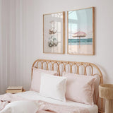 Cuadro de sombrilla rosa con flecos sobre playa de arena clara, mar azul sereno y cielo pastel, en estilo fotográfico. Disponible en kudeko.com
