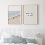 Cuadro de playa luminosa con arena beige, orilla de piedras claras, mar azul suave y velero lejano, de estilo fotográfico. Disponible en kudeko.com