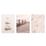 Set aus drei Wandbildern mit Muscheln am Strand, Holzsteg zum Meer, hellem Sand, Altrosa, Weiß, sanftem Beige und fotografischem Küstenstil. Erhältlich auf kudeko.com