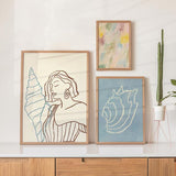 Conjunto de três quadros com mulher de perfil, conchas marinhas, composição em azul celeste, bege, rosa suave e estilo de ilustração com inspiração de verão. Disponível em kudeko.com