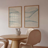 Set aus zwei gerahmten Wandbildern mit vom Meer inspirierten Wellenlinien, hellblauen Tönen, elfenbeinfarbenem Hintergrund und ruhigem abstraktem Stil für eine ausgewogene Wandgestaltung. Erhältlich auf kudeko.com