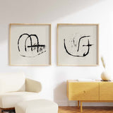 Conjunto de dos cuadros con símbolos abstractos en negro sobre fondo beige claro, composición sobria de líneas orgánicas y estilo abstracto. Disponible en kudeko.com