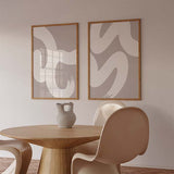Conjunto de dos cuadros abstractos con trazos curvos en blanco sobre fondo beige kudeko.com