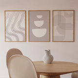 Conjunto de tres cuadros con líneas curvas orgánicas, formas semicirculares superpuestas y composición abstracta en tonos beige, topo, arena y blanco, de estilo minimalista. Disponible en kudeko.com