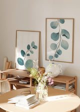 Ensemble de deux tableaux avec fines branches botaniques, feuilles arrondies bleu vert, aigue-marine et vert doux, dans un style floral épuré sur fond blanc. Disponible sur kudeko.com