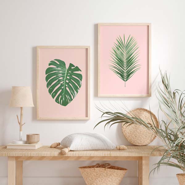Conjunto de dois quadros emoldurados com folha de monstera e palmeira estilizada em verde sobre fundo rosa suave, num estilo floral contemporâneo e equilibrado. Disponível em kudeko.com