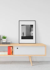 Cuadro de sombras de dos personas sobre pared urbana de hormigón y puerta metálica, en tonos blanco, negro y gris, de estilo fotográfico. Disponible en kudeko.com