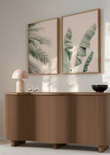 Set aus zwei Wandbildern mit Bananenblättern und Palmblättern, sanften Grüntönen, hellrosa Hintergrund und Natur Landschaftsstil für eine ruhige Wandgestaltung. Erhältlich auf kudeko.com