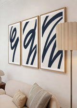 Conjunto de três quadros com formas curvas abstratas em azul-marinho, fundo branco quebrado e composição contínua em estilo contemporâneo para decoração de parede. Disponível em kudeko.com