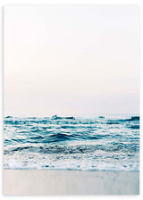 Gerahmtes Wandbild mit ruhigem Meer, sanften Wellen am Ufer, hellem Sand, lichtdurchflutetem Himmel sowie Türkisblau, Weiß und Beige in fotografischem Stil. Erhältlich auf kudeko.com
